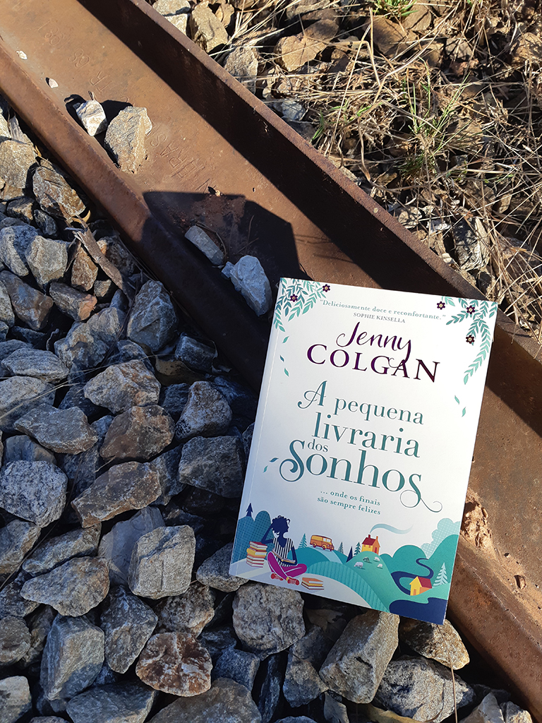 Livro colocado sobre linha do trem, representando as quotes e trechos de A Pequena Livraria dos Sonhos, de Jenny Colgan, publicado pela Editora Arqueiro em 2019.